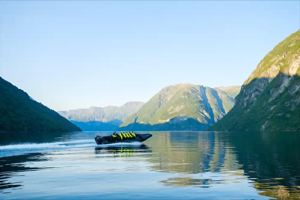 The boat alone on a mirror-calm fjord between peaks