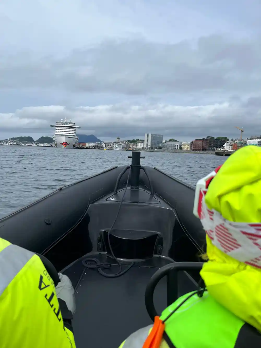 The bow of the RIB pointing at Alesund and a cruise ship