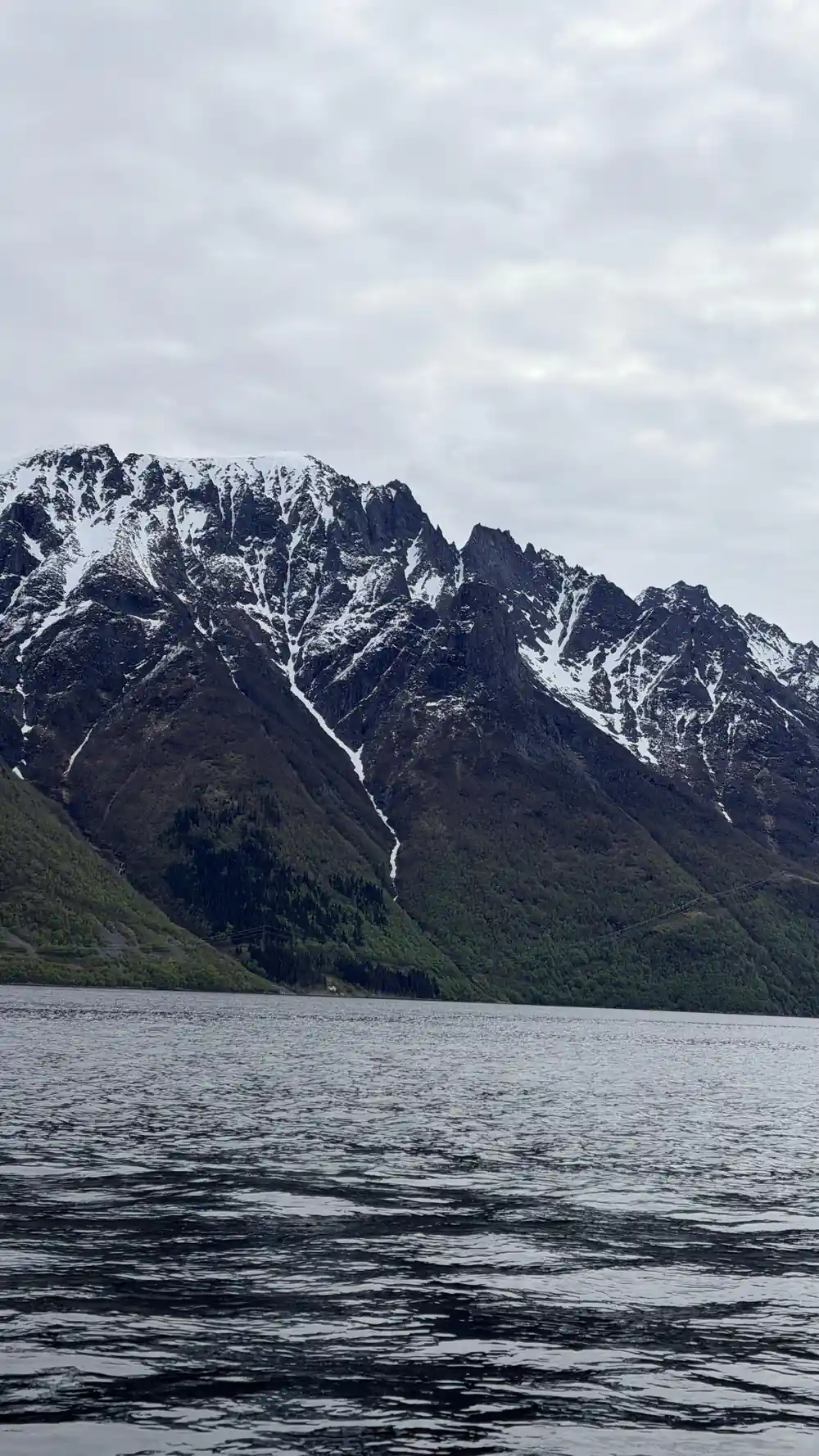 A dark snow-streaked mountain wall above the water