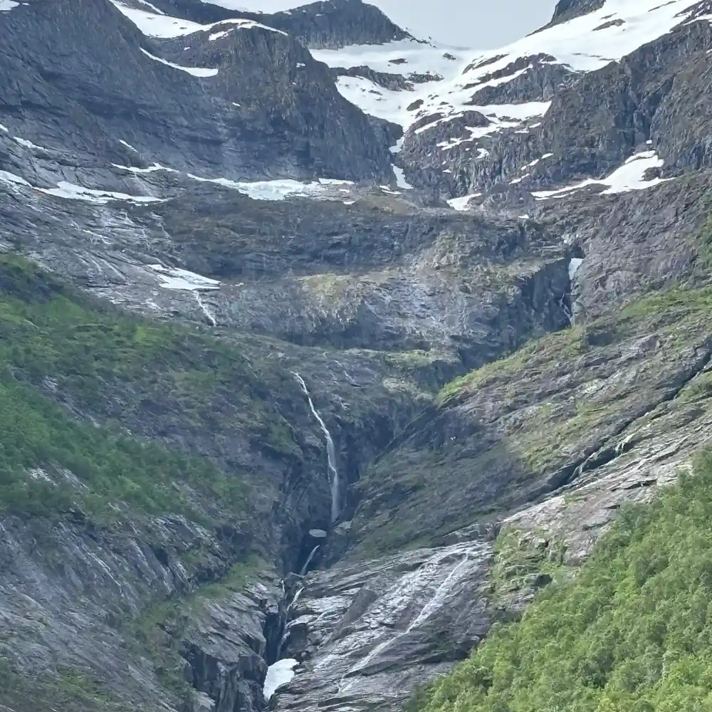A long waterfall falling down a grey rock face