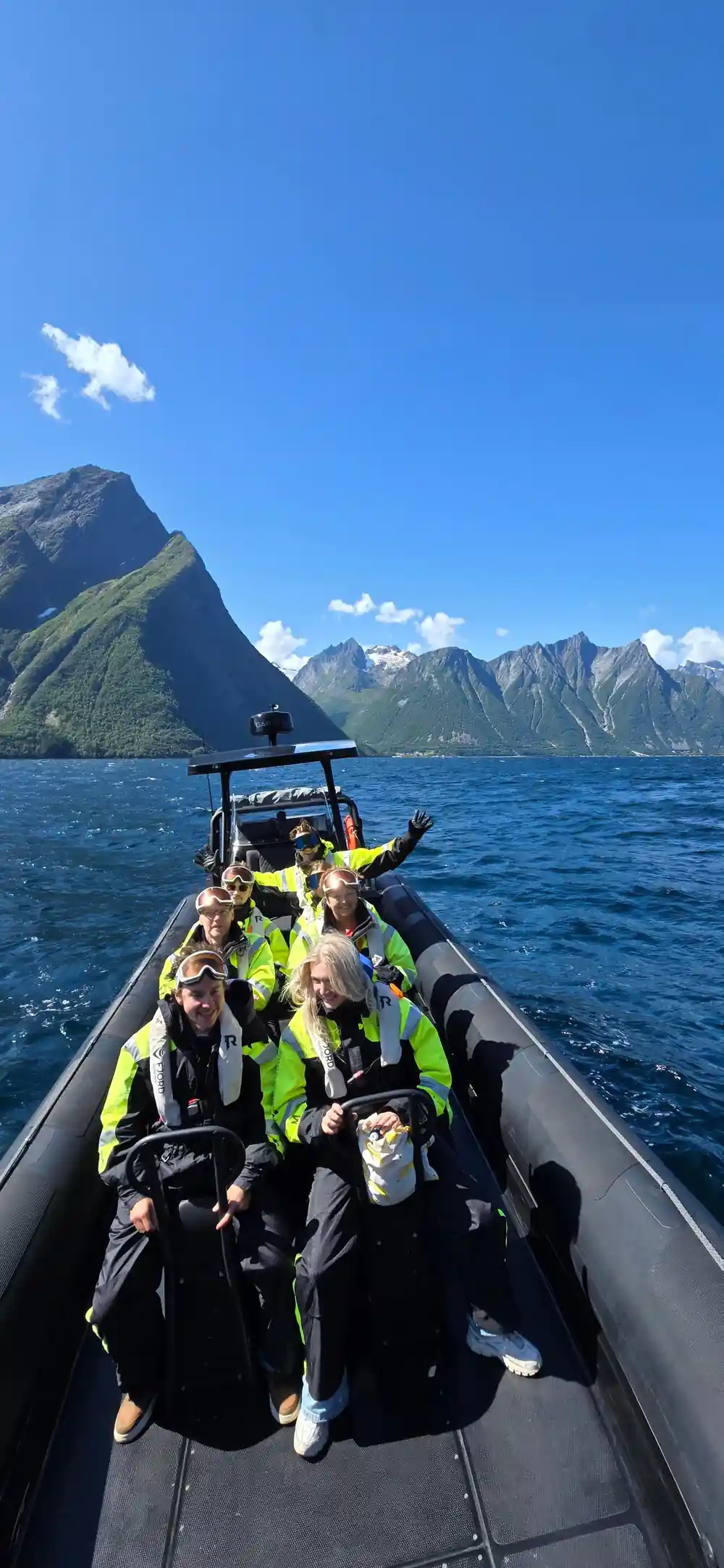 Passengers waving from the RIB with the Sunnmore Alps behind