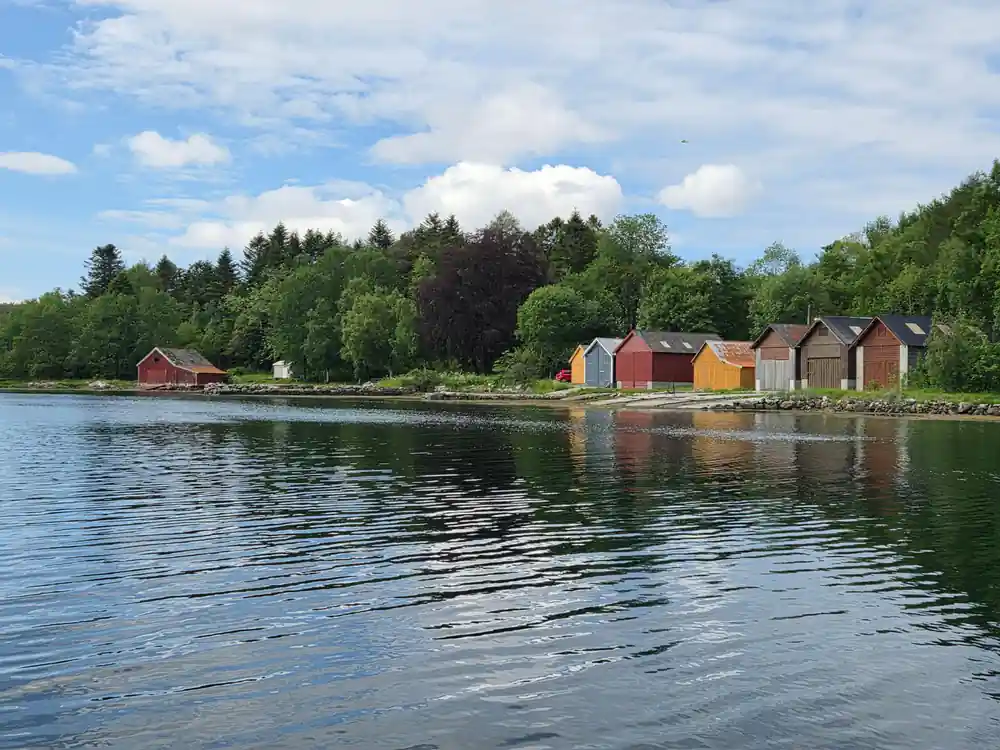 Red and ochre boathouses along a calm shoreline
