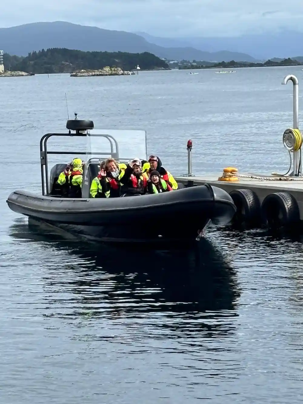 The RIB alongside the quay loaded with passengers in yellow suits