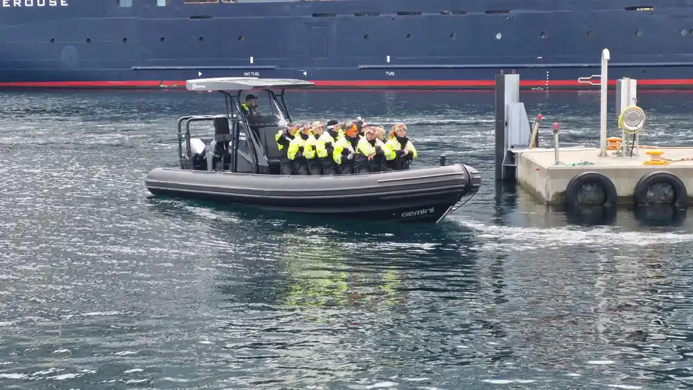 The RIB running past the hull of a cruise ship