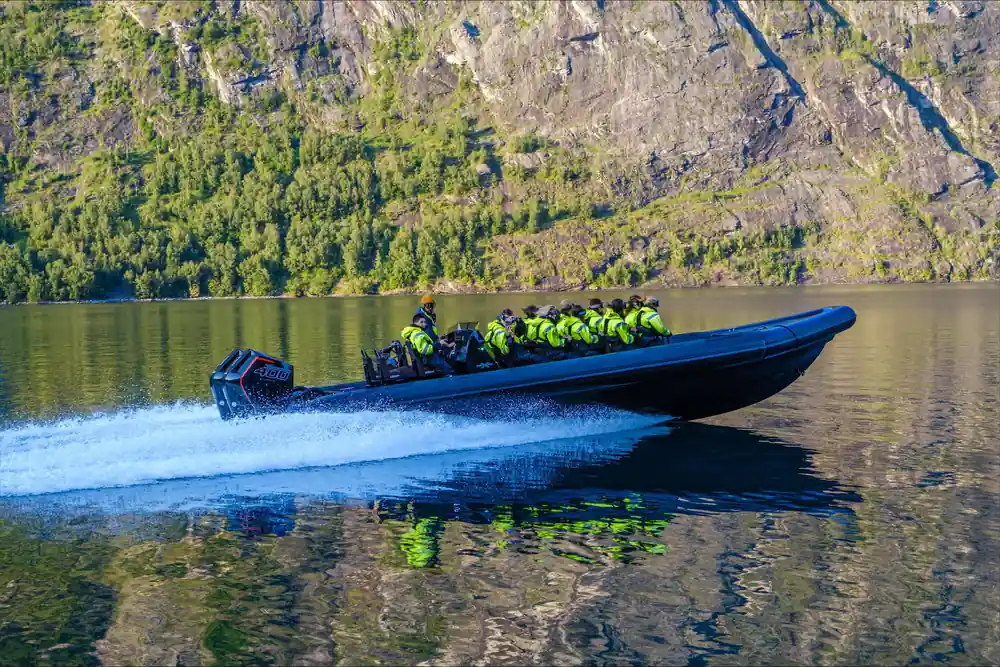 The RIB under way at speed below a rock wall