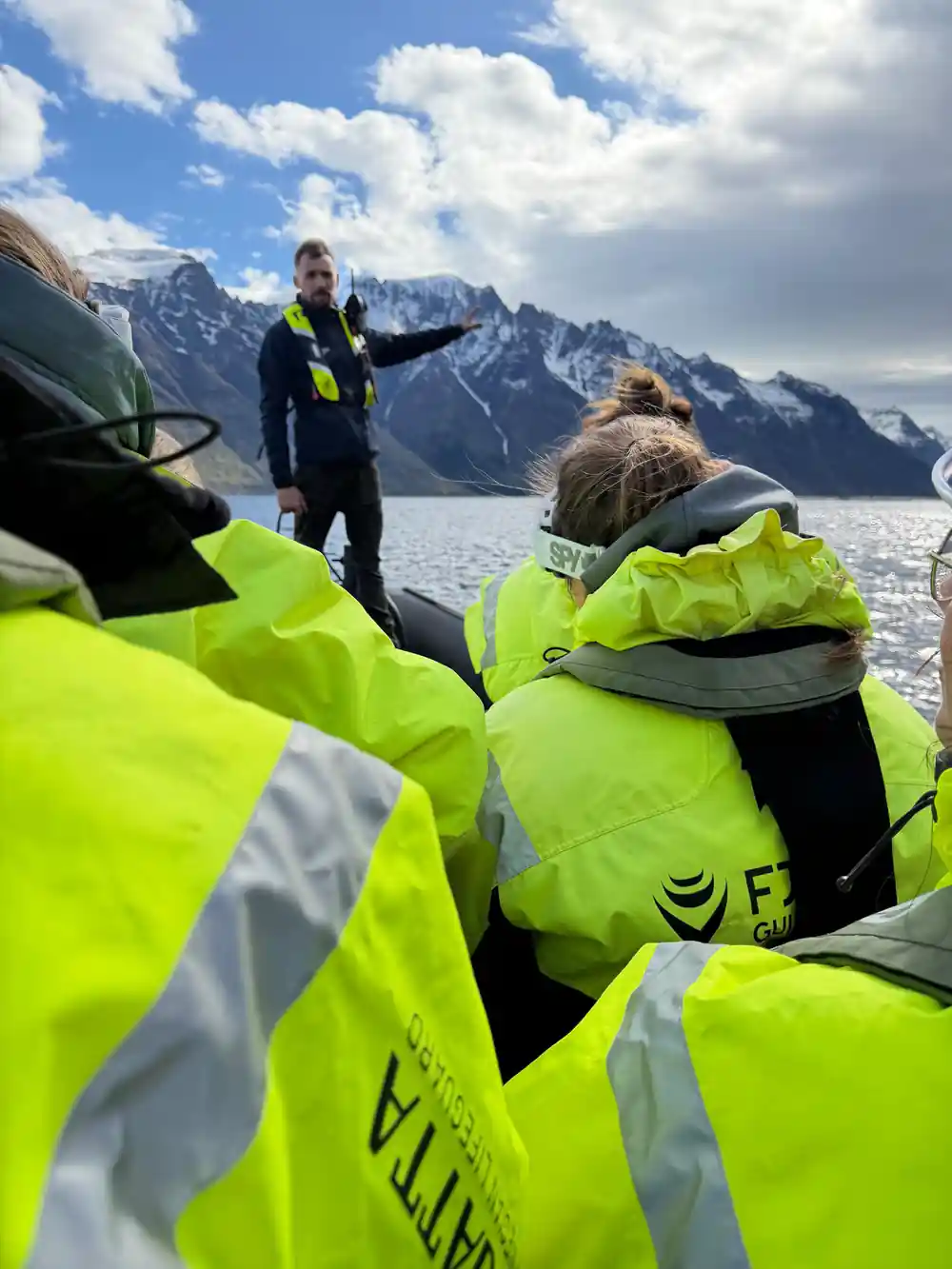 The skipper pointing at a snow-capped ridge for passengers