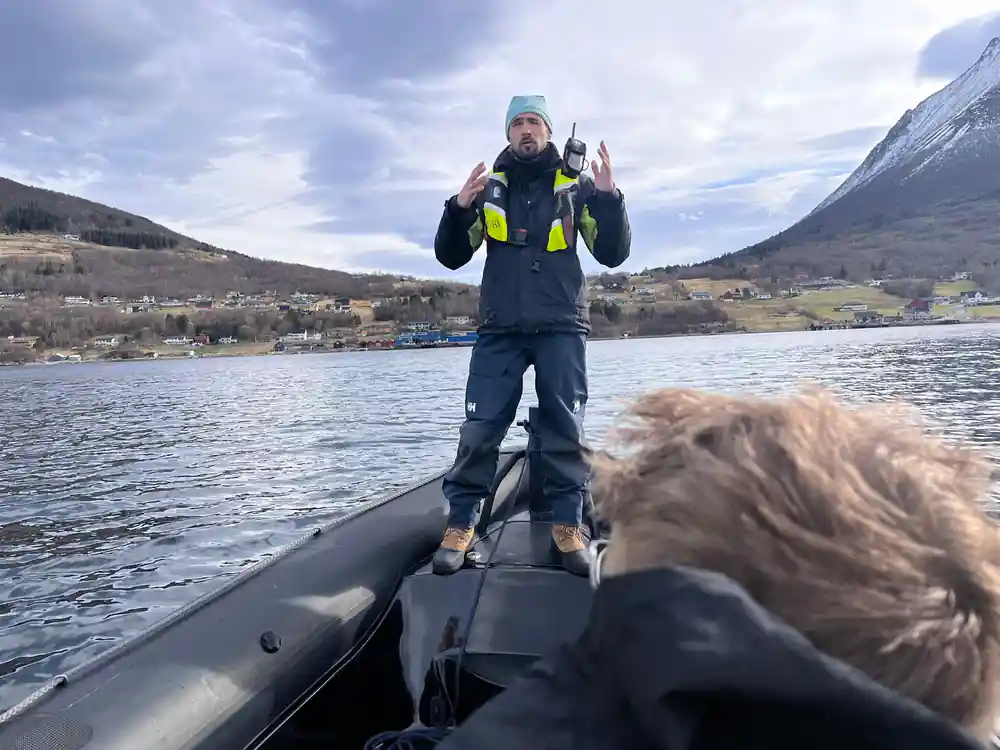 The skipper talking from the bow with mountains behind