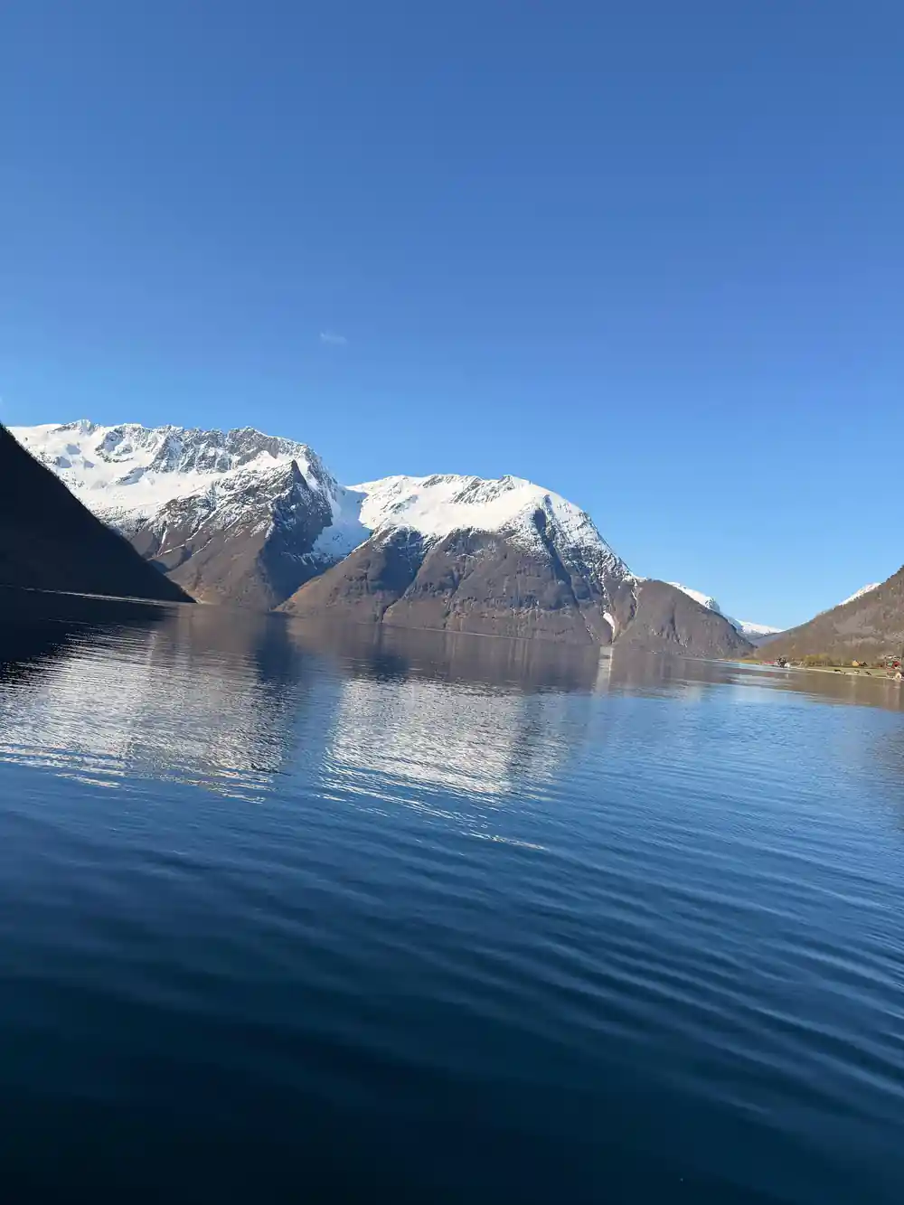A snow-covered mountain mirrored in flat calm water