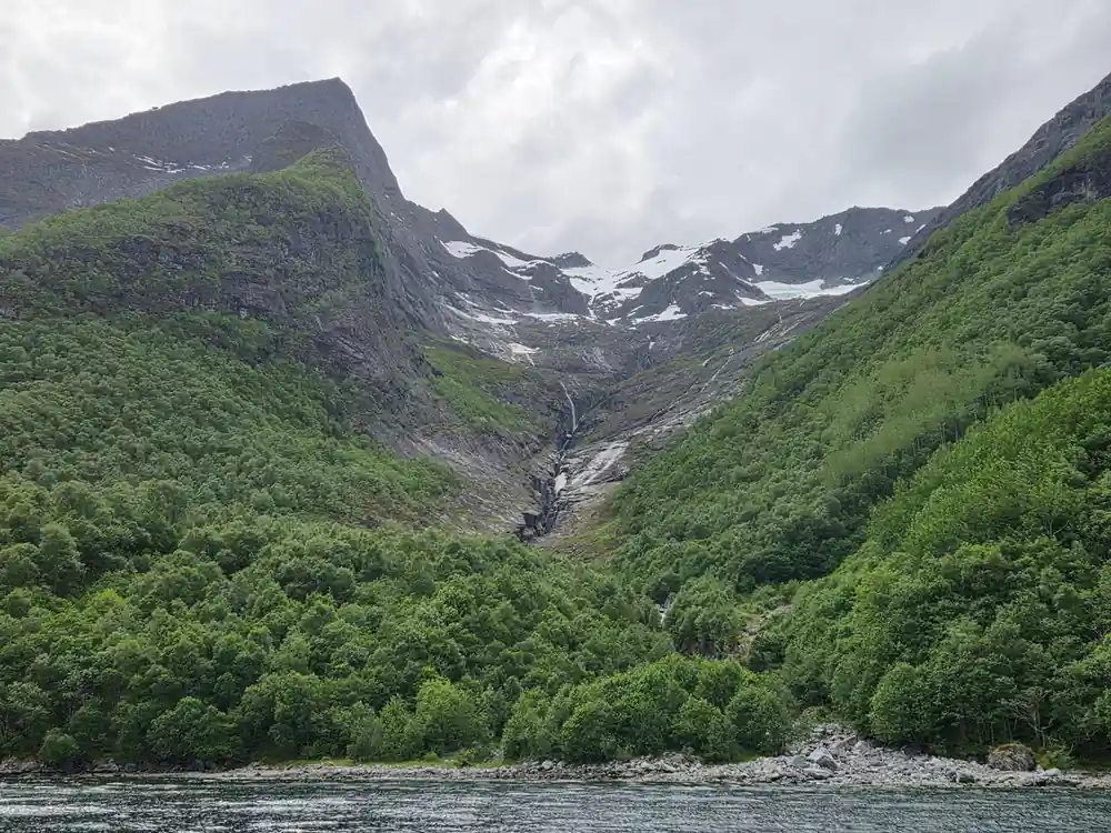 A snow-filled corrie high above the green fjord side