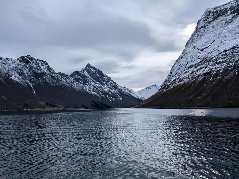 Snowy peaks at the head of a still fjord