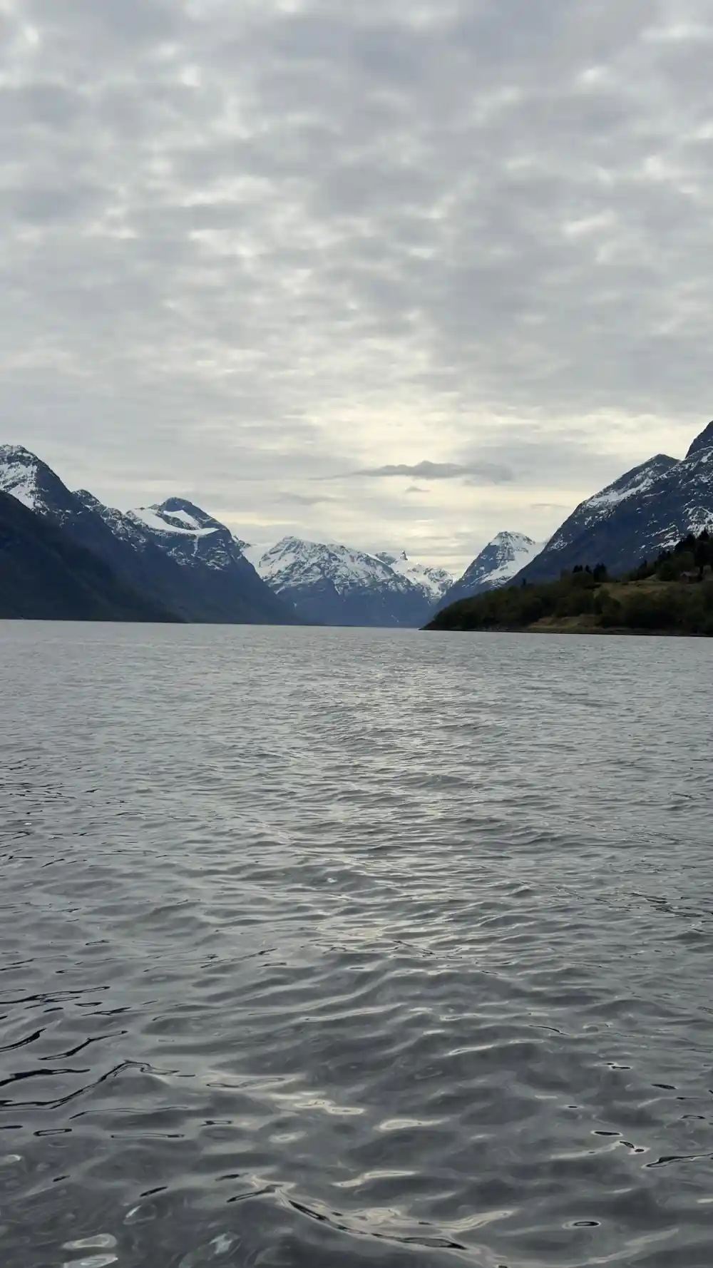 A wide grey fjord running away between mountains